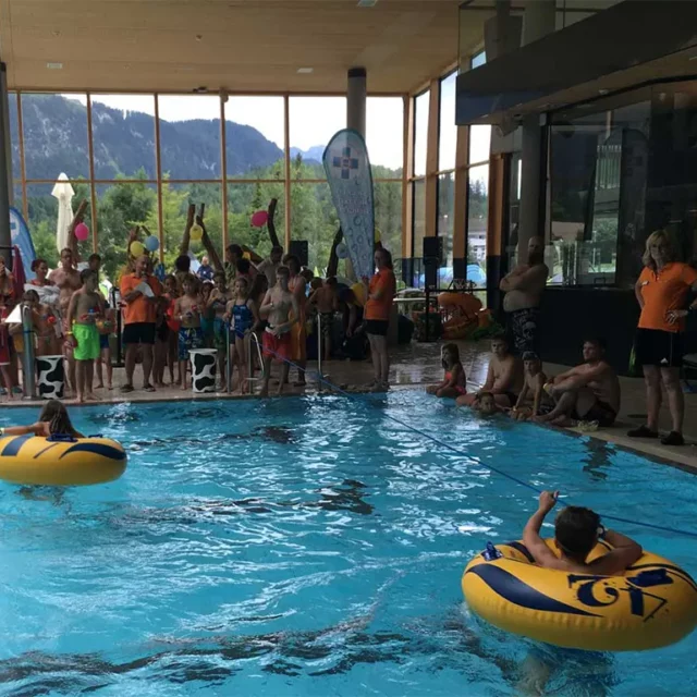 Kinder mit Schwimmreifen an einer Leine im Wasser