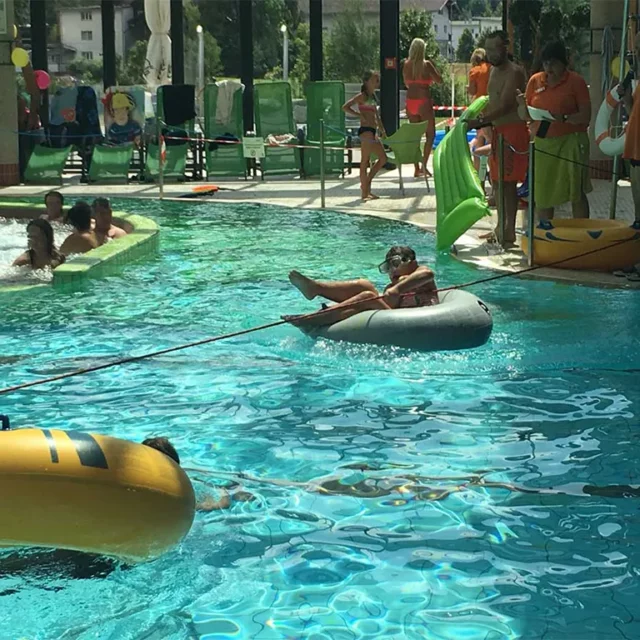 Junge mit einem Schwimmreifen an einer Leine im Wasser