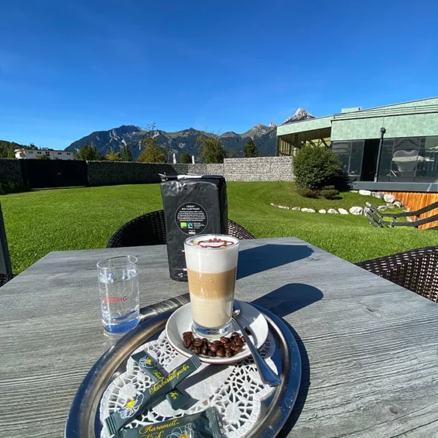 eine Kaffeespezialität und ein Glas Wasser auf der Terrasse