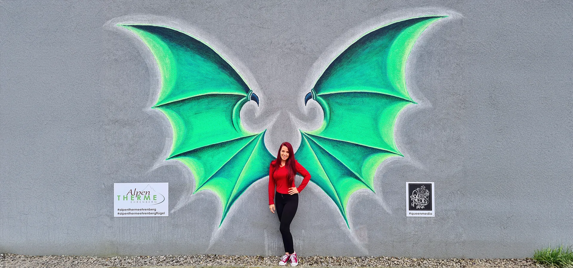 Bettina vor den gezeichnete Drachenflügeln an der Wand